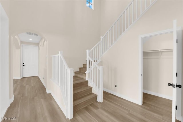 177 Rocky Star St, Henderson, NV 89012 - stairs featuring wood finished floors, a towering ceiling, arched walkways, and baseboards