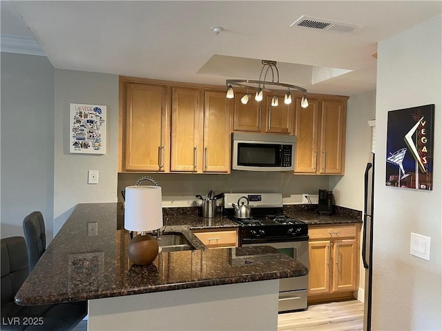 260 E Flamingo Rd Unit 228, Las Vegas, NV 89169 - kitchen featuring stainless steel appliances, a peninsula, dark stone countertops, light wood-style flooring, and a kitchen breakfast bar
