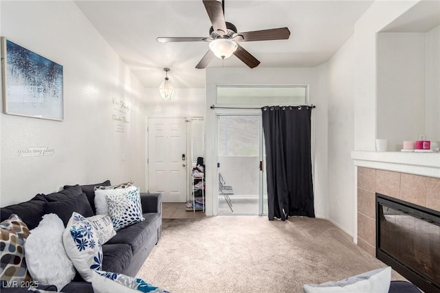 living area with carpet, ceiling fan, a tiled fireplace, and baseboards