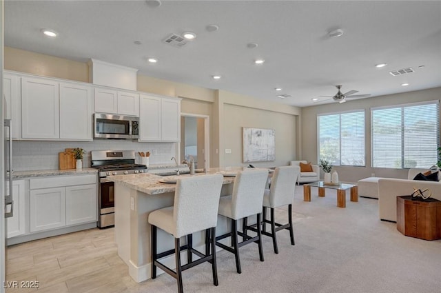 9903 Spinel Pl, Las Vegas, NV 89143 - kitchen with stainless steel appliances, open floor plan, backsplash, a sink, and a center island with sink