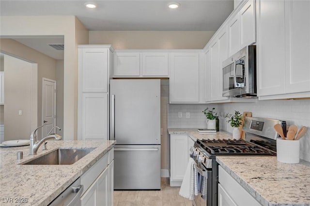 9903 Spinel Pl, Las Vegas, NV 89143 - kitchen featuring appliances with stainless steel finishes, a sink, white cabinets, light stone countertops, and backsplash