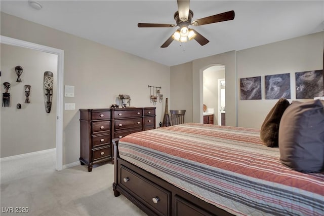 9046 Barium Rock Ave, Las Vegas, NV 89143 - bedroom featuring arched walkways, light colored carpet, baseboards, connected bathroom, and a ceiling fan