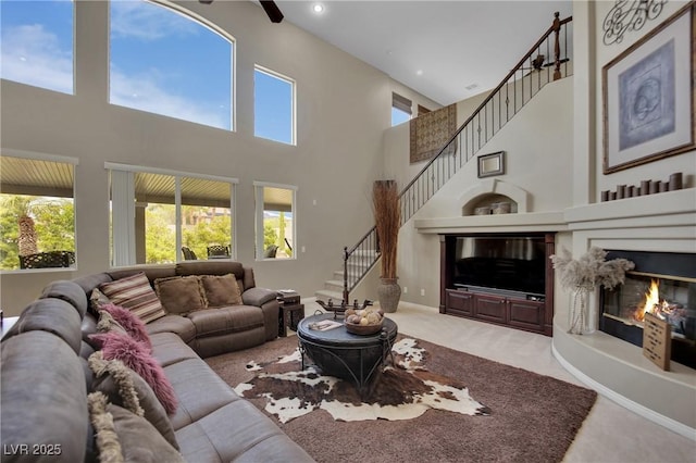 9046 Barium Rock Ave, Las Vegas, NV 89143 - living area with carpet, a high ceiling, plenty of natural light, stairway, and a glass covered fireplace