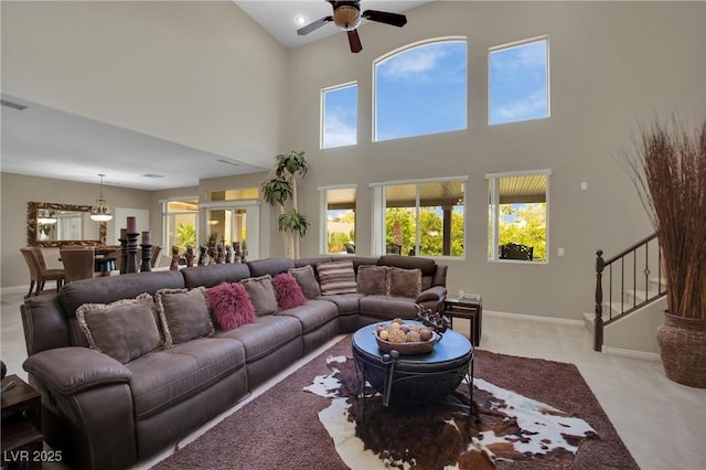 9046 Barium Rock Ave, Las Vegas, NV 89143 - living room featuring light carpet, ceiling fan, baseboards, a high ceiling, and stairs