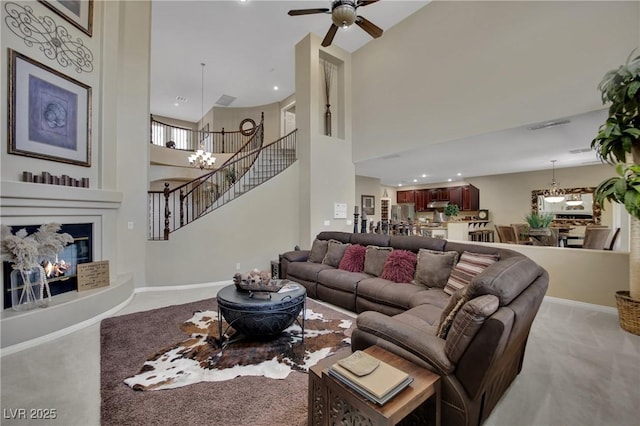9046 Barium Rock Ave, Las Vegas, NV 89143 - carpeted living area with stairs, ceiling fan, a towering ceiling, a chandelier, and a glass covered fireplace
