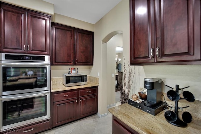 9046 Barium Rock Ave, Las Vegas, NV 89143 - kitchen with appliances with stainless steel finishes, dark brown cabinets, arched walkways, and baseboards
