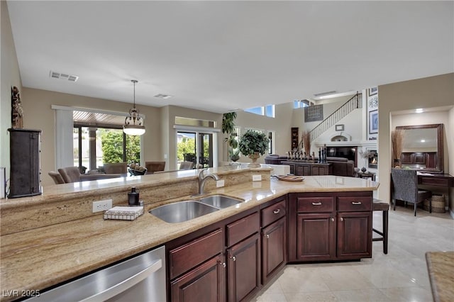 9046 Barium Rock Ave, Las Vegas, NV 89143 - kitchen with a sink, open floor plan, stainless steel dishwasher, a kitchen bar, and hanging light fixtures