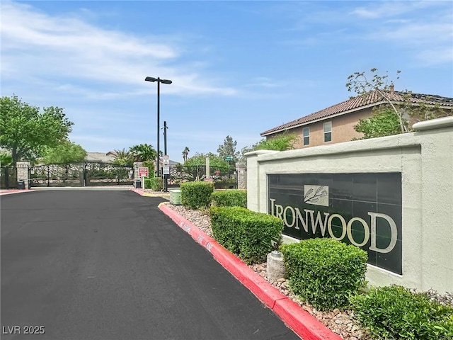 9046 Barium Rock Ave, Las Vegas, NV 89143 - view of asphalt road with street lighting, a gate, curbs, and a gated entry