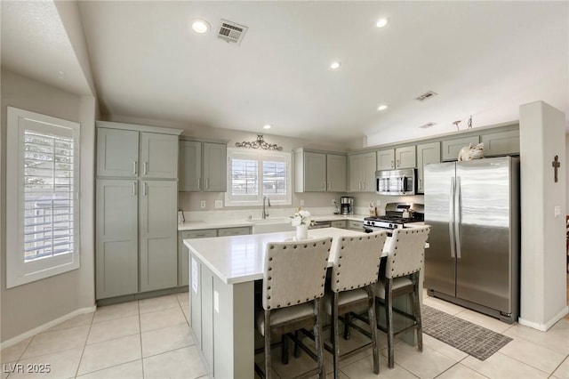 6021 Winter Meadow St, Las Vegas, NV 89130 - kitchen featuring appliances with stainless steel finishes, gray cabinetry, a kitchen island, light countertops, and light tile patterned floors