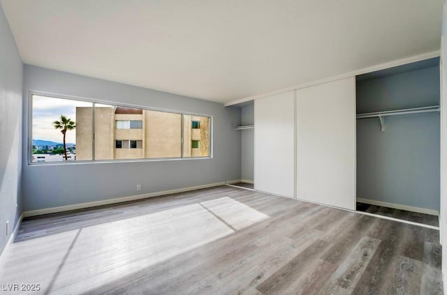 745 N Royal Crest Cir Unit 141, Las Vegas, NV 89169 - unfurnished bedroom with multiple windows, wood finished floors, a closet, and baseboards