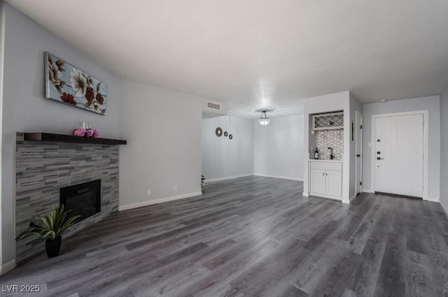 745 N Royal Crest Cir Unit 141, Las Vegas, NV 89169 - unfurnished living room featuring a tiled fireplace, dark wood-style flooring, and baseboards