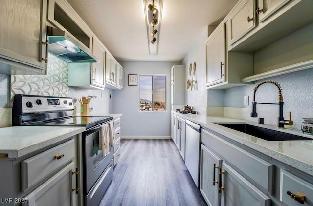 745 N Royal Crest Cir Unit 141, Las Vegas, NV 89169 - kitchen featuring appliances with stainless steel finishes, a sink, wood finished floors, decorative backsplash, and under cabinet range hood