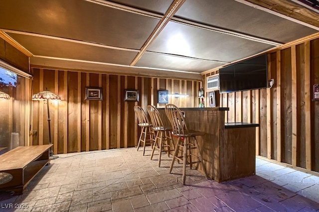 indoor dry bar featuring stone tile floors and wood walls