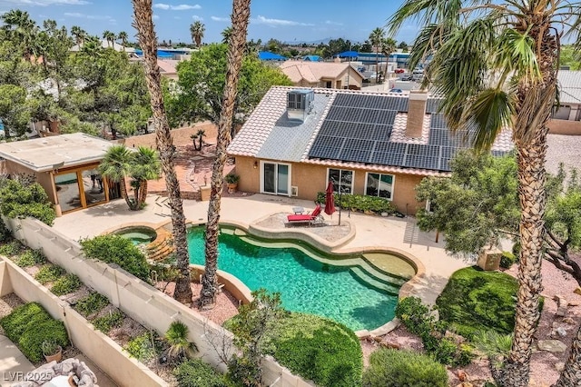 back of house featuring an in-ground hot tub, stucco siding, a patio, a tile roof, and roof mounted solar panels