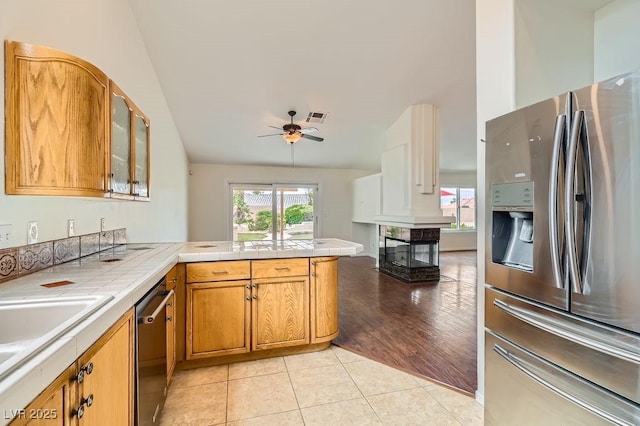 3619 Bixbee Ct, Las Vegas, NV 89129 - kitchen featuring appliances with stainless steel finishes, tile counters, a peninsula, ceiling fan, and glass insert cabinets
