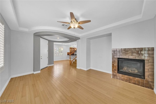 2432 Granada Bluff Ct, Las Vegas, NV 89135 - unfurnished living room with a raised ceiling, a fireplace, ceiling fan, arched walkways, and wood finished floors