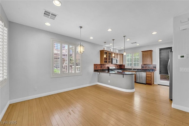 2432 Granada Bluff Ct, Las Vegas, NV 89135 - kitchen featuring stainless steel appliances, dark countertops, a peninsula, glass insert cabinets, and a breakfast bar