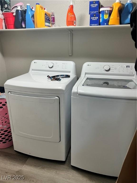 clothes washing area with separate washer and dryer and wood finished floors