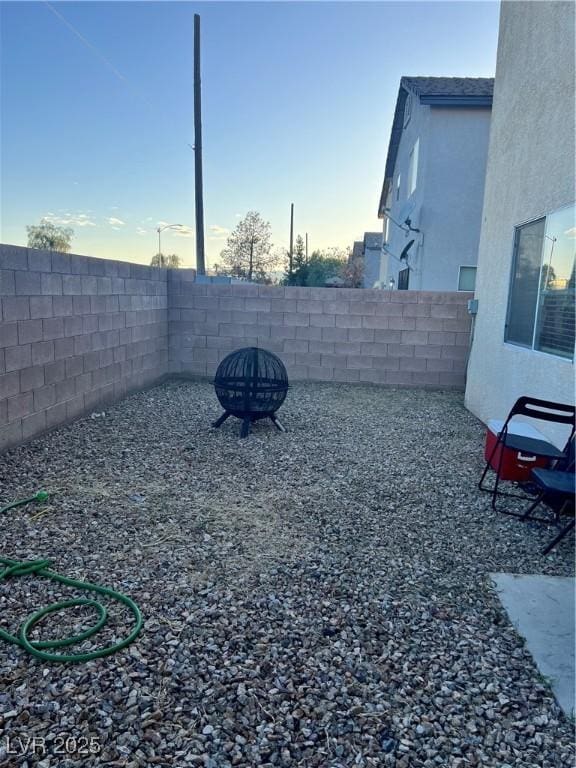 yard at dusk featuring a fenced backyard