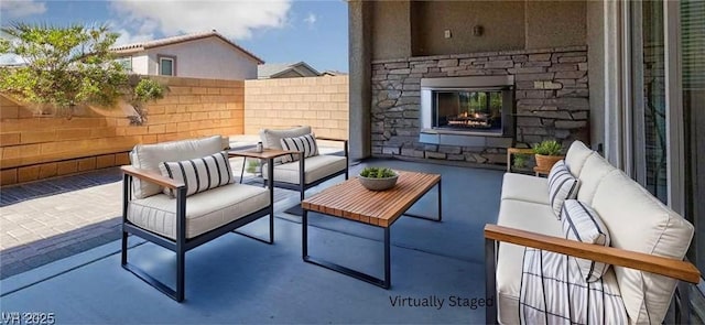 view of patio / terrace with an outdoor living space with a fireplace and fence