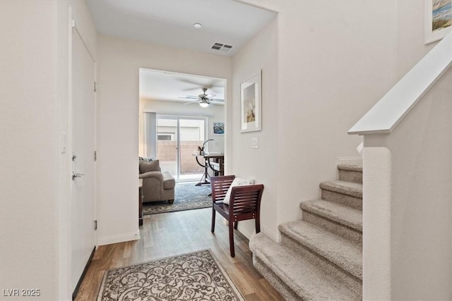hall featuring stairway, wood finished floors, and baseboards