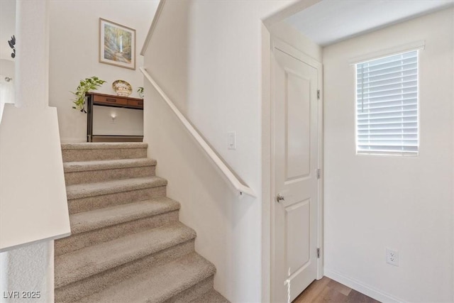 staircase featuring healthy amount of natural light, wood finished floors, and baseboards