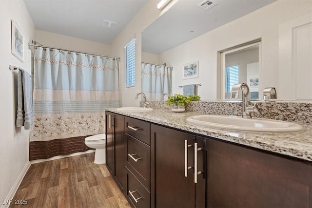 full bathroom featuring toilet, wood finished floors, plenty of natural light, and double vanity
