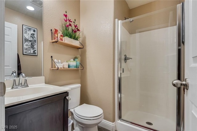 bathroom featuring a shower stall, toilet, a textured wall, and vanity