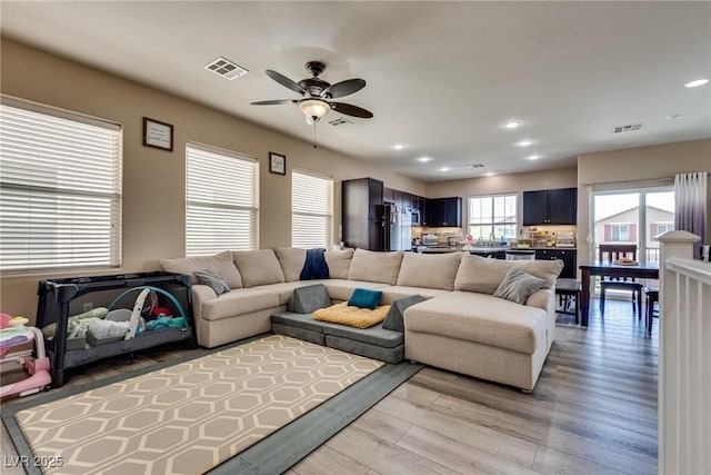 living room with a ceiling fan, light wood-style floors, and recessed lighting
