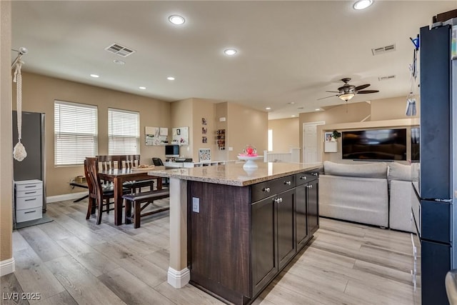kitchen with open floor plan, dark brown cabinets, baseboards, a ceiling fan, and light wood-type flooring