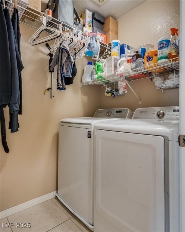 washroom with washer and clothes dryer, light tile patterned flooring, and baseboards