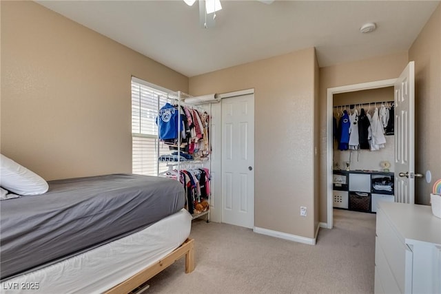 bedroom featuring light colored carpet, baseboards, a closet, and ceiling fan