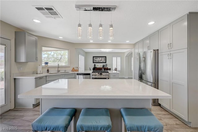 4 Tarryall Ter, Henderson, NV 89074 - kitchen featuring stainless steel appliances, a sink, gray cabinetry, a kitchen bar, and recessed lighting