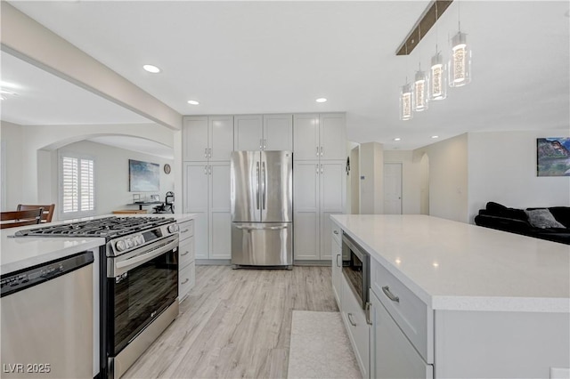 4 Tarryall Ter, Henderson, NV 89074 - kitchen featuring appliances with stainless steel finishes, arched walkways, light wood finished floors, light countertops, and recessed lighting