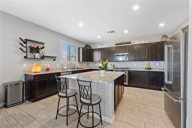 3854 Stadium Ave, Las Vegas, NV 89120 - kitchen featuring stainless steel appliances, wood tiled floors, a center island, a breakfast bar area, and dark brown cabinets