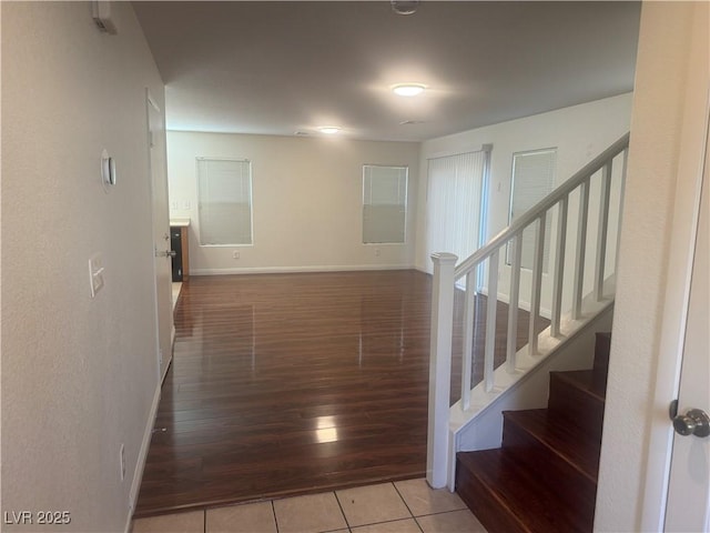 corridor featuring stairway, tile patterned floors, and baseboards