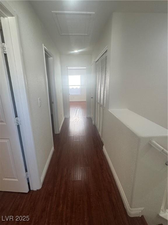 corridor featuring wood finished floors, attic access, and baseboards