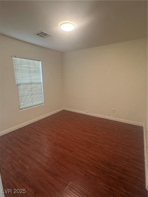 unfurnished room featuring dark wood-style flooring and baseboards