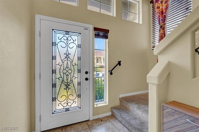 tiled foyer entrance featuring stairs, baseboards, and carpet flooring