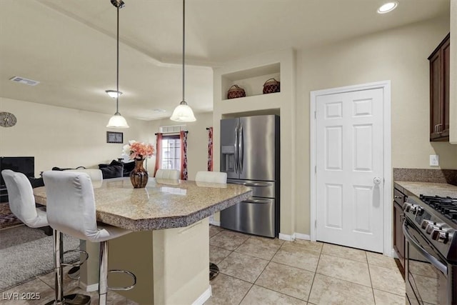 kitchen with stainless steel refrigerator with ice dispenser, black gas stove, light countertops, a breakfast bar, and a kitchen island