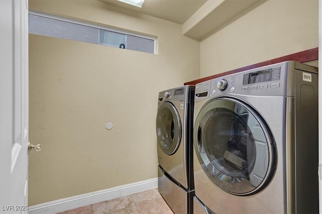 clothes washing area with washing machine and dryer, baseboards, and tile patterned floors
