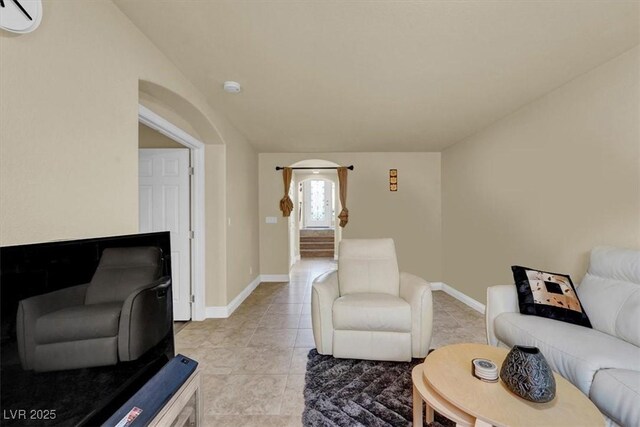 living room featuring an AC wall unit, light tile patterned flooring, and baseboards