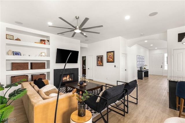 8317 Fritzen Ave, Las Vegas, NV 89131 - living room with a ceiling fan, arched walkways, a glass covered fireplace, light wood finished floors, and recessed lighting