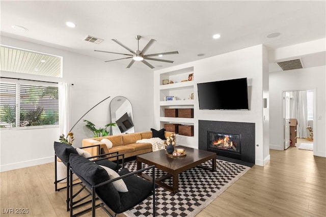 8317 Fritzen Ave, Las Vegas, NV 89131 - living area with light wood-style flooring, built in shelves, a glass covered fireplace, baseboards, and ceiling fan