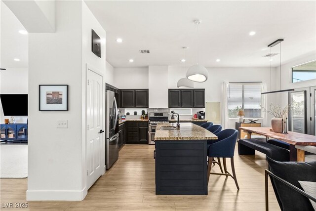 8317 Fritzen Ave, Las Vegas, NV 89131 - kitchen featuring appliances with stainless steel finishes, light stone counters, recessed lighting, an island with sink, and a sink