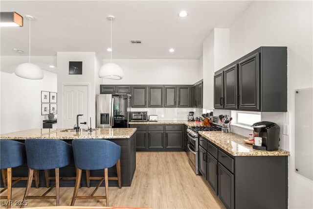 8317 Fritzen Ave, Las Vegas, NV 89131 - kitchen with appliances with stainless steel finishes, a sink, light stone counters, a breakfast bar area, and recessed lighting