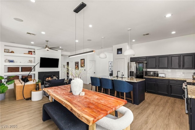 8317 Fritzen Ave, Las Vegas, NV 89131 - dining space featuring ceiling fan, light wood finished floors, a warm lit fireplace, and recessed lighting