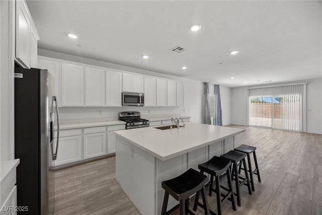 3706 Etendre Ct, Las Vegas, NV 89121 - kitchen with appliances with stainless steel finishes, a breakfast bar, a sink, a kitchen island with sink, and light wood-style floors
