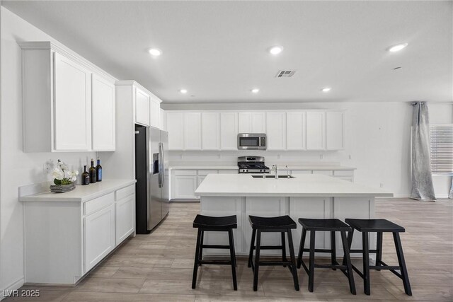 3706 Etendre Ct, Las Vegas, NV 89121 - kitchen featuring stainless steel appliances, a kitchen bar, light countertops, light wood-type flooring, and recessed lighting