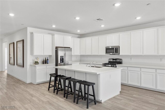 3706 Etendre Ct, Las Vegas, NV 89121 - kitchen featuring appliances with stainless steel finishes, a sink, a breakfast bar area, light wood-style floors, and recessed lighting
